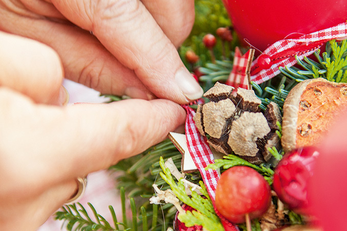 Bänder und andere zarte Deko­ befestigt man besser mit Stecknadeln auf dem Adventskranz