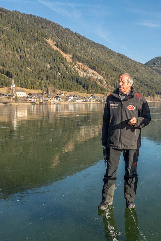 Der Eismeister vom Weißensee steht auf spiegelblankem Eis