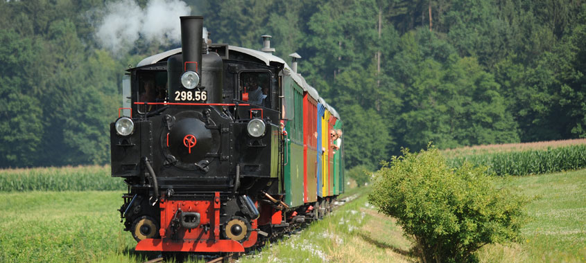 Zug mit bunten Waggons wird von einer Dampflok gezogen