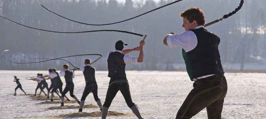 Januarbräuche-Burschen in Tracht schwingen bis zu 4 Meter lange Peitschen