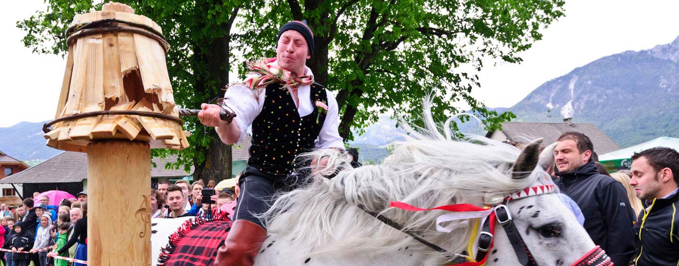 Ein Bursche in Tracht reitet auf einem Pferd und zerschlägt den Kufen beim Kufenstechen in Feistritz