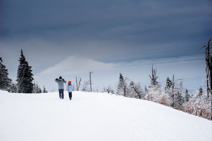 Warten - Vater und Sohn spazieren durch eine Schneelandschaft