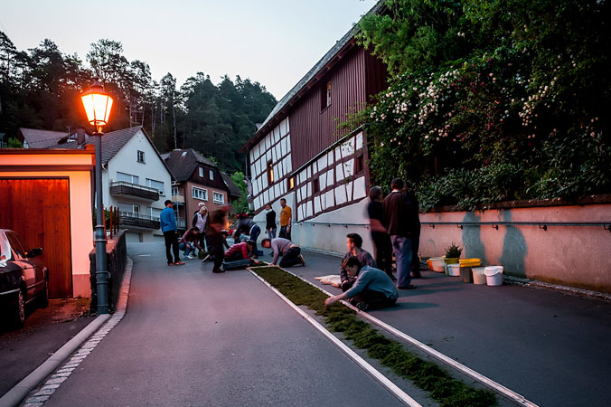 Am frühen Morgen beginnen bereits die Vorbereitungen Im Morgengrauen bereiten mehrere Menschen den Blumenteppich auf der Straße vor