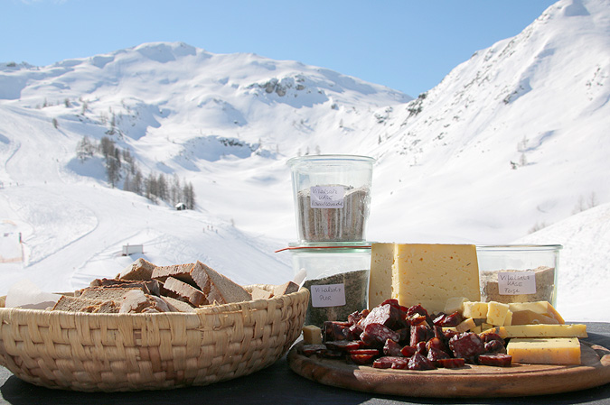 Käse, Wurst und Salz aus dem Alpenland, präsentiert vor verschneiter Bergkulisse Veranstaltungstipps März: Der höchstgelegene Bauernmarkt der Alpen